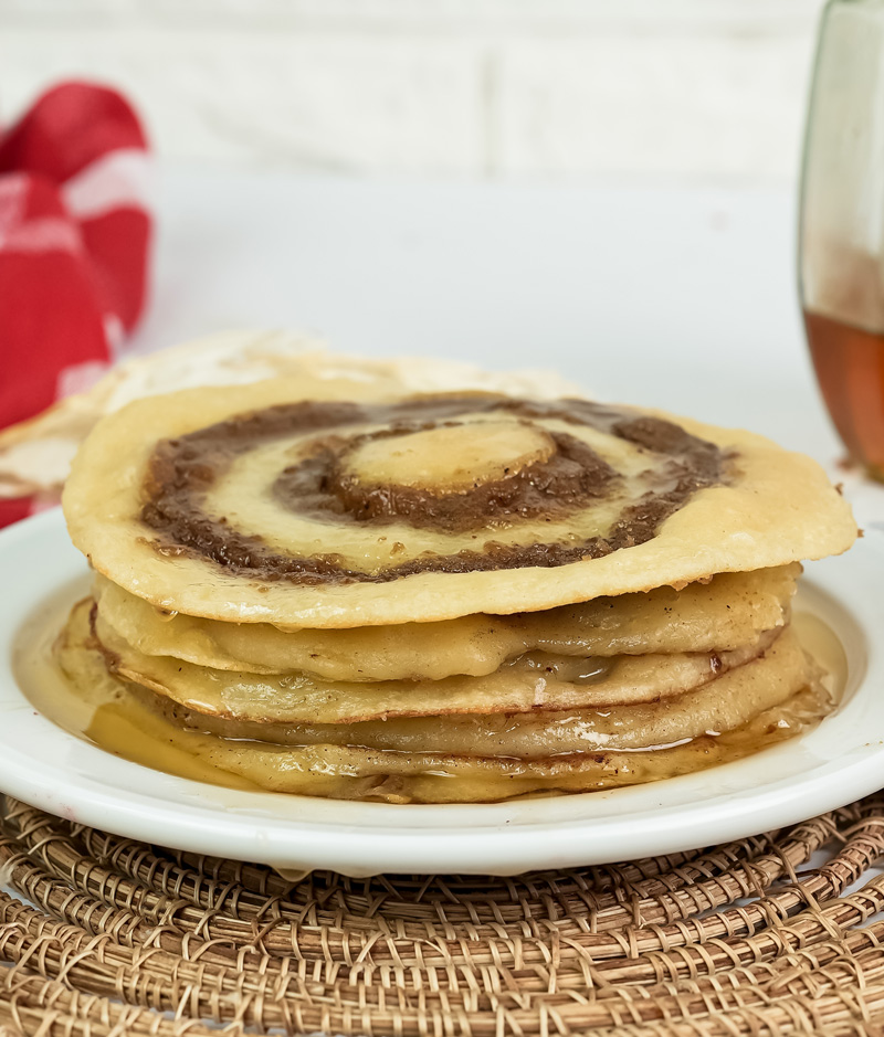 Stack of fluffy cinnamon roll pancakes with visible cinnamon swirls