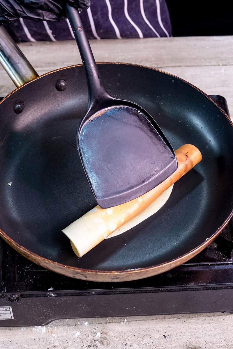 Lifting golden pancake roll with spatula while cooking