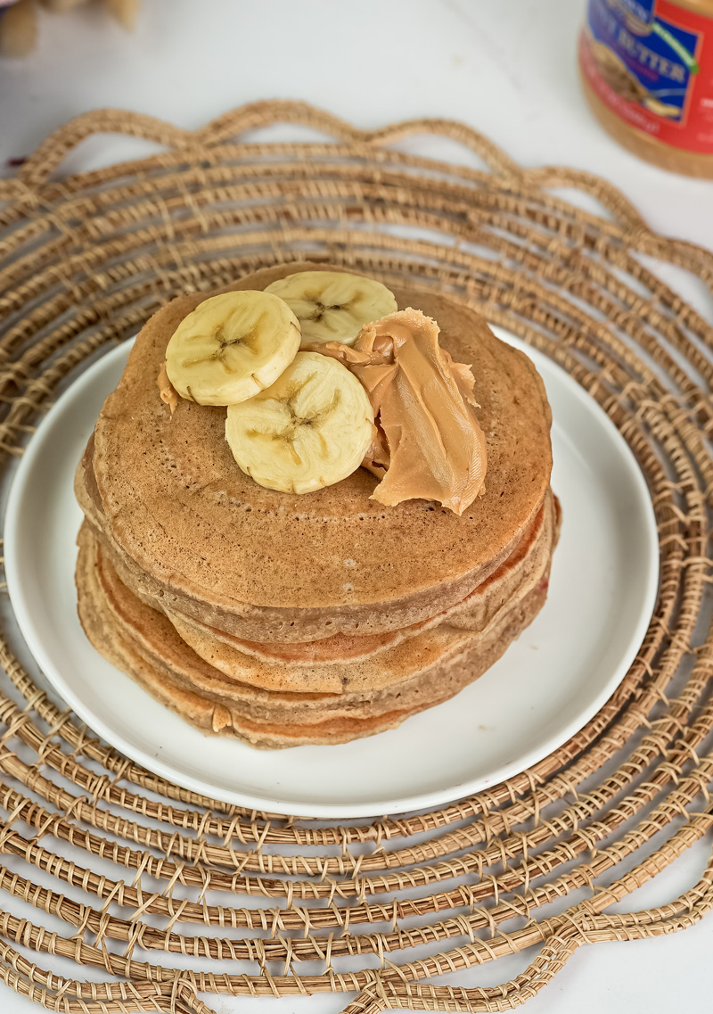 Stack of peanut butter pancakes topped with banana slices and peanut butter