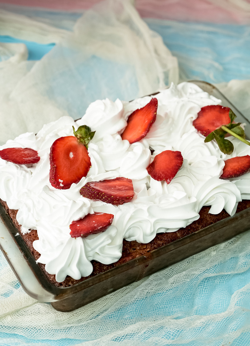 Finished strawberry earthquake cake with white frosting and strawberry garnish