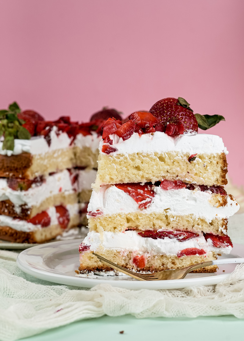 Individual strawberry shortcake slice garnished with fresh strawberries on plate
