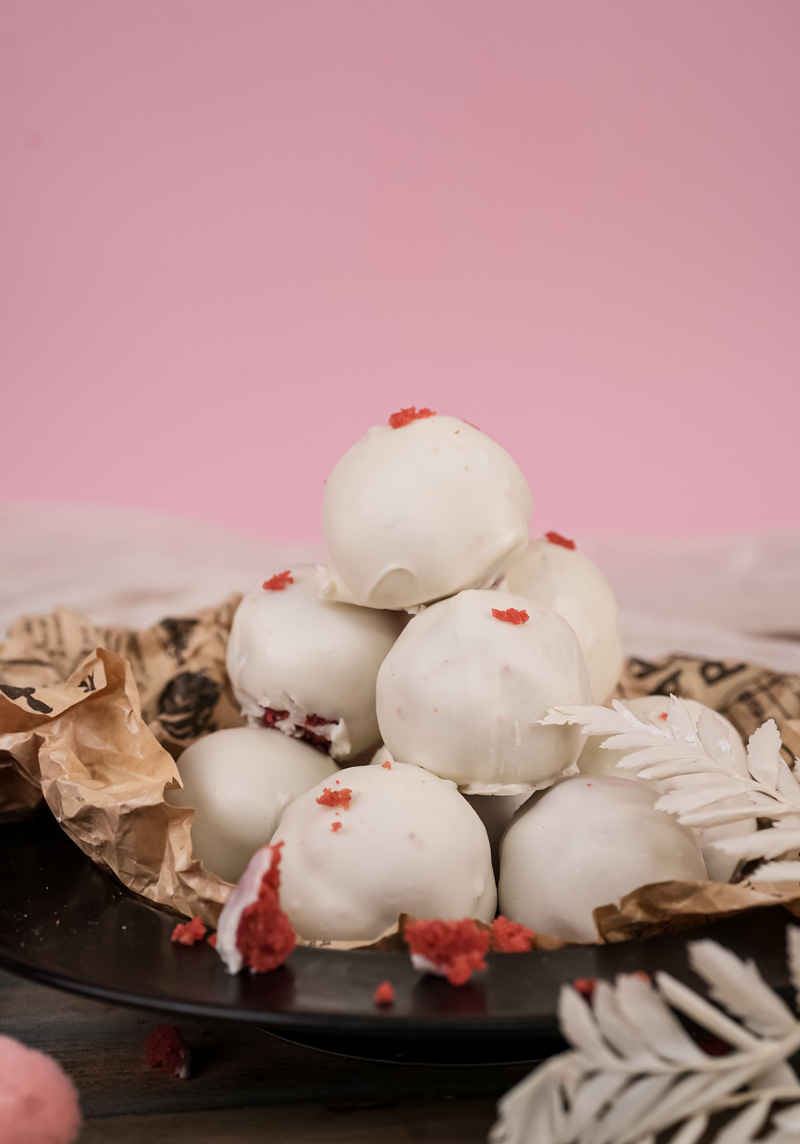 Elegant presentation of white-coated strawberry cake pops with decorative elements