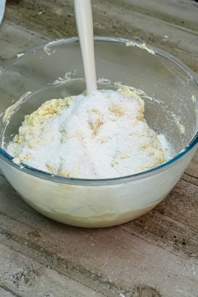 Adding granulated sugar to the creamed butter for the banana bread batter.