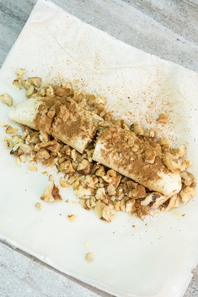 Cinnamon being dusted over banana walnut strudel filling