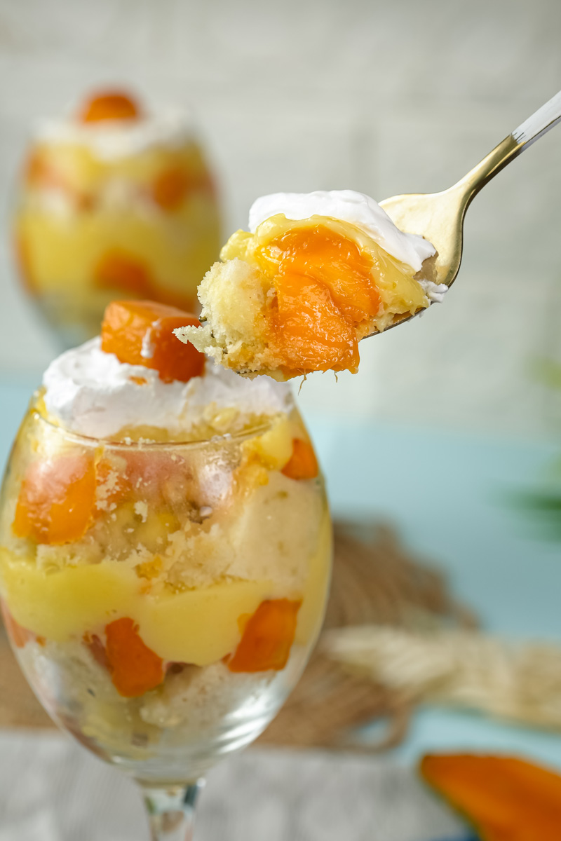 Creamy mango trifle spoonful with visible fruit pieces