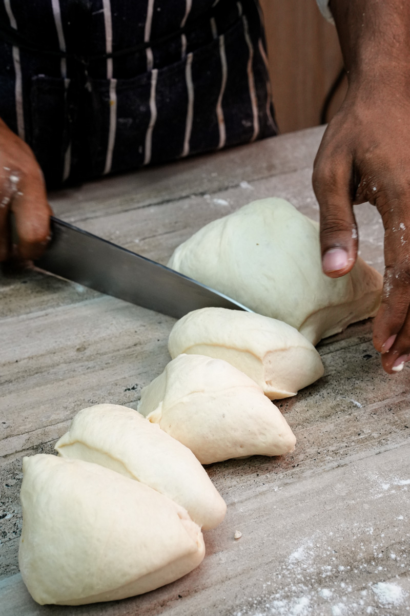 Dividing bread bowl dough into equal portions on a floured surface.
