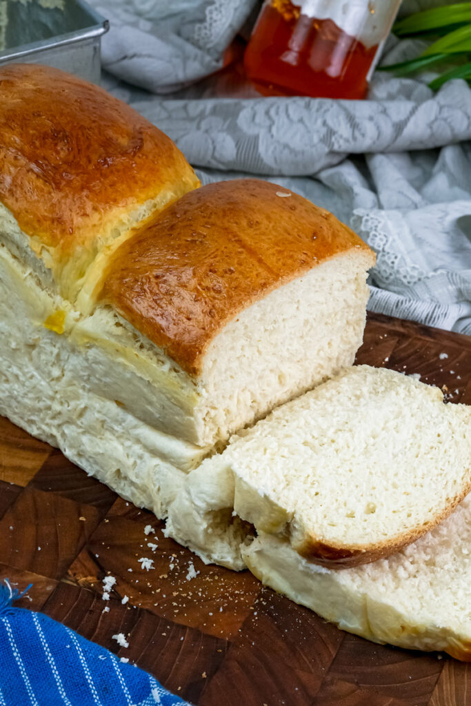 Fluffy Japanese milk bread slices with golden crust on wooden board