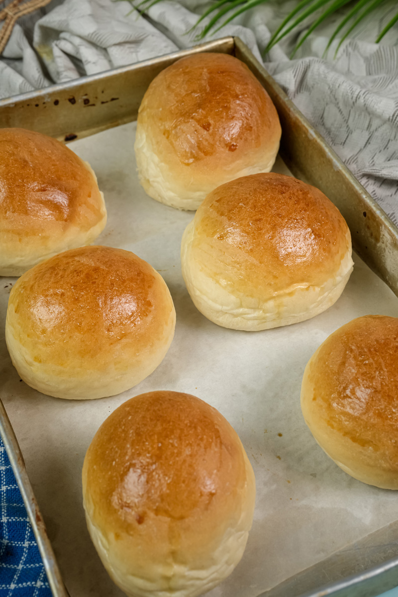 Freshly baked golden brown bread bowls cooling on a baking sheet.