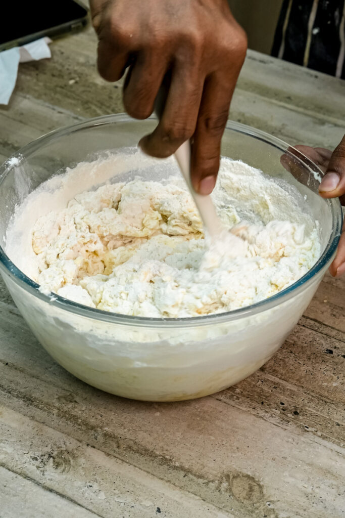 Gently mixing the flour into the wet banana bread ingredients with a spatula.