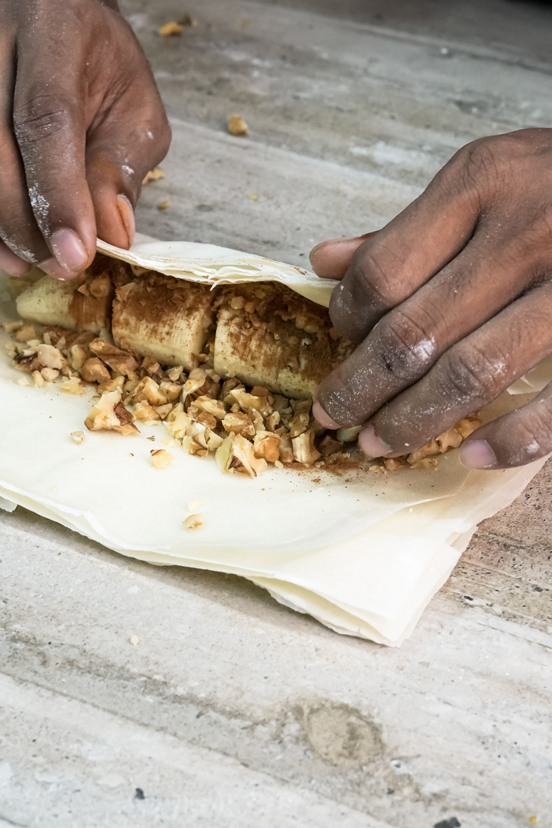 Hands wrapping banana filling in phyllo pastry dough