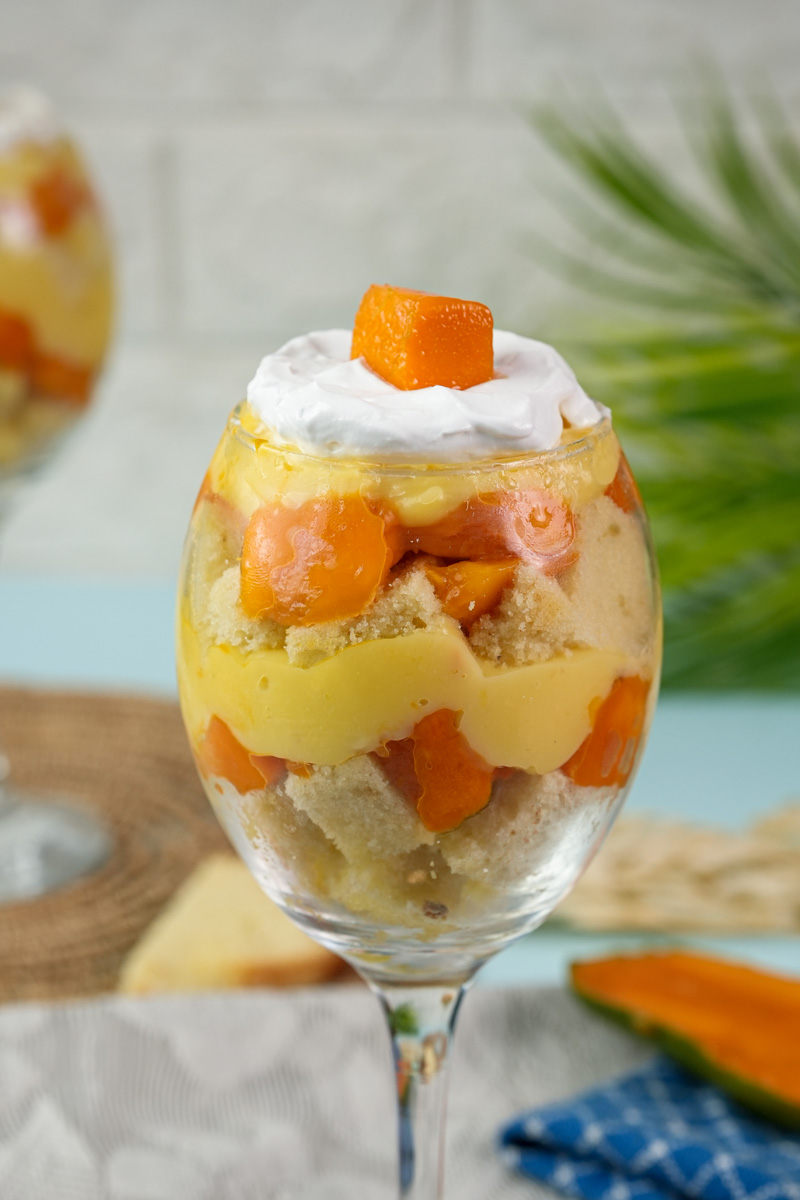 Close-up of layered mango trifle dessert in wine glass