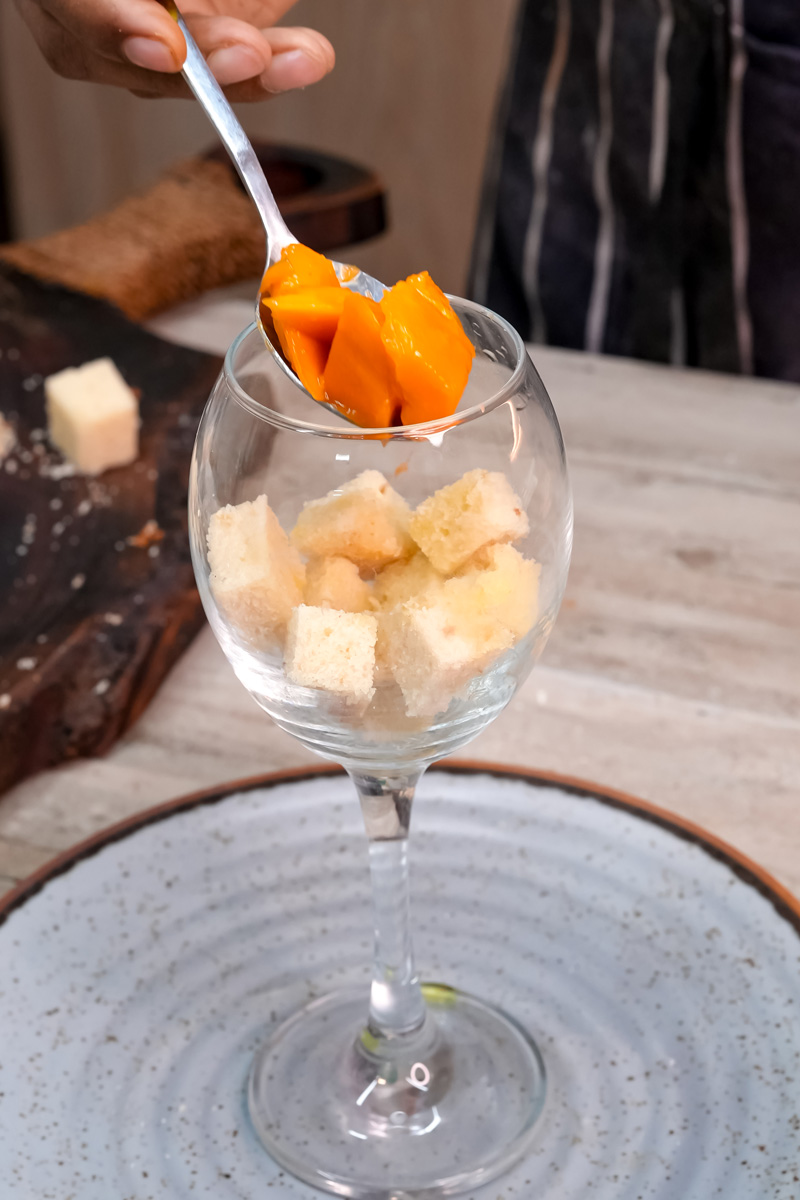 Layering fresh mango pieces in trifle glass