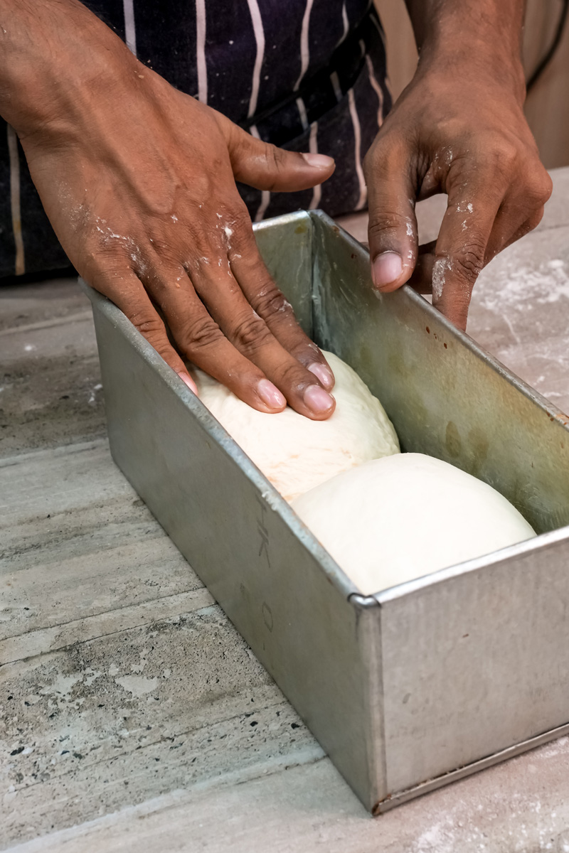 Placing Japanese bread dough portions into metal loaf pan