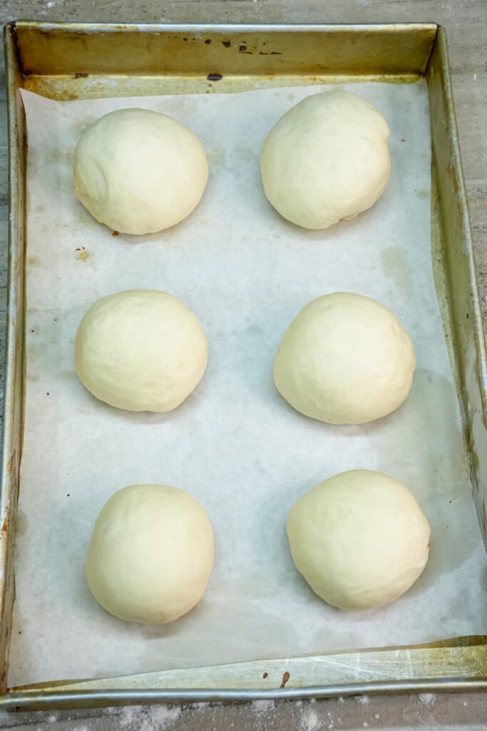 Shaped dough balls on a parchment-lined baking sheet, ready for the second proof.