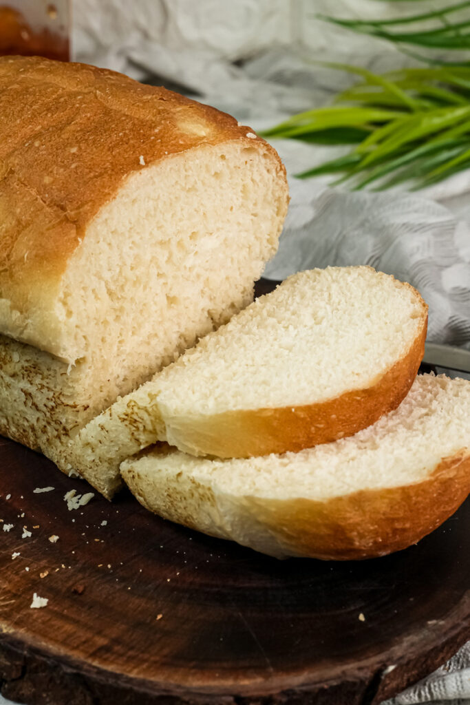 A slice of English Muffin Bread topped with orange marmalade, with the loaf in the background.