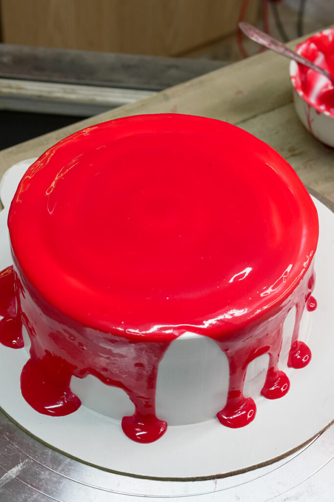 A frosted cake covered in a vibrant red drip glaze