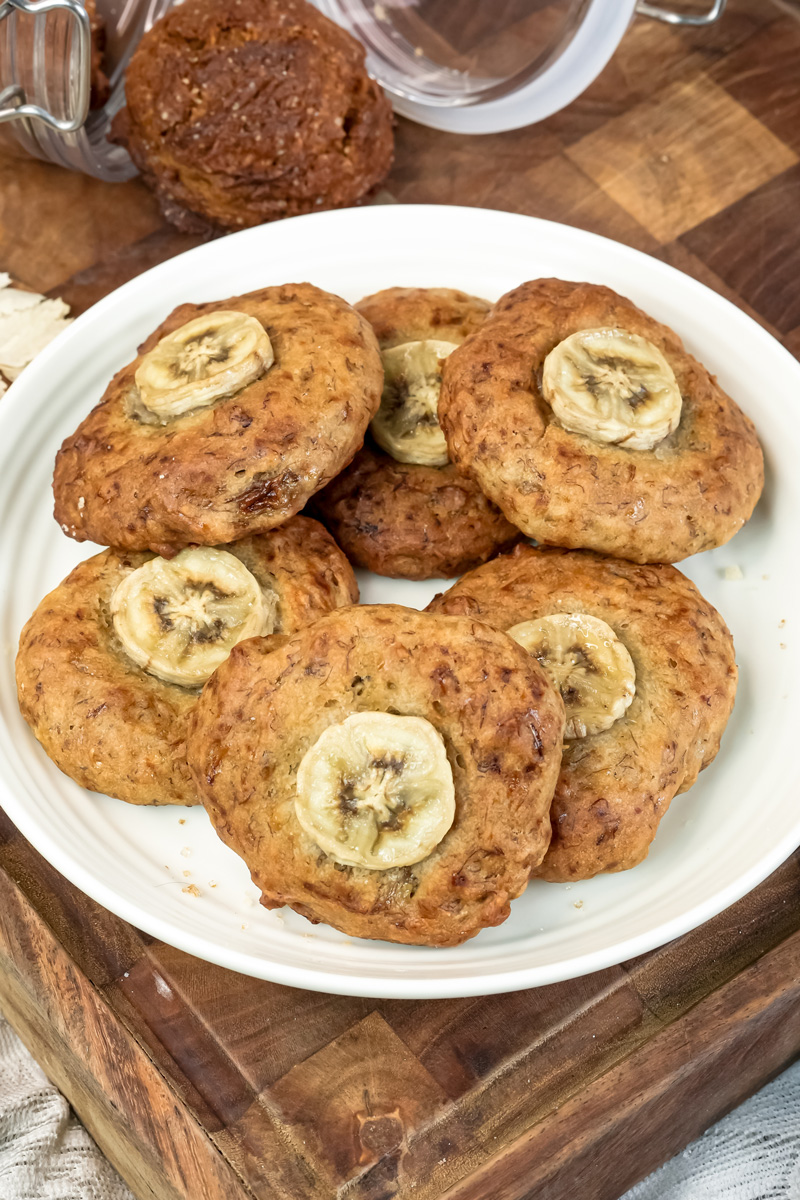 A plate of golden-brown banana cookies, each topped with a slice of banana