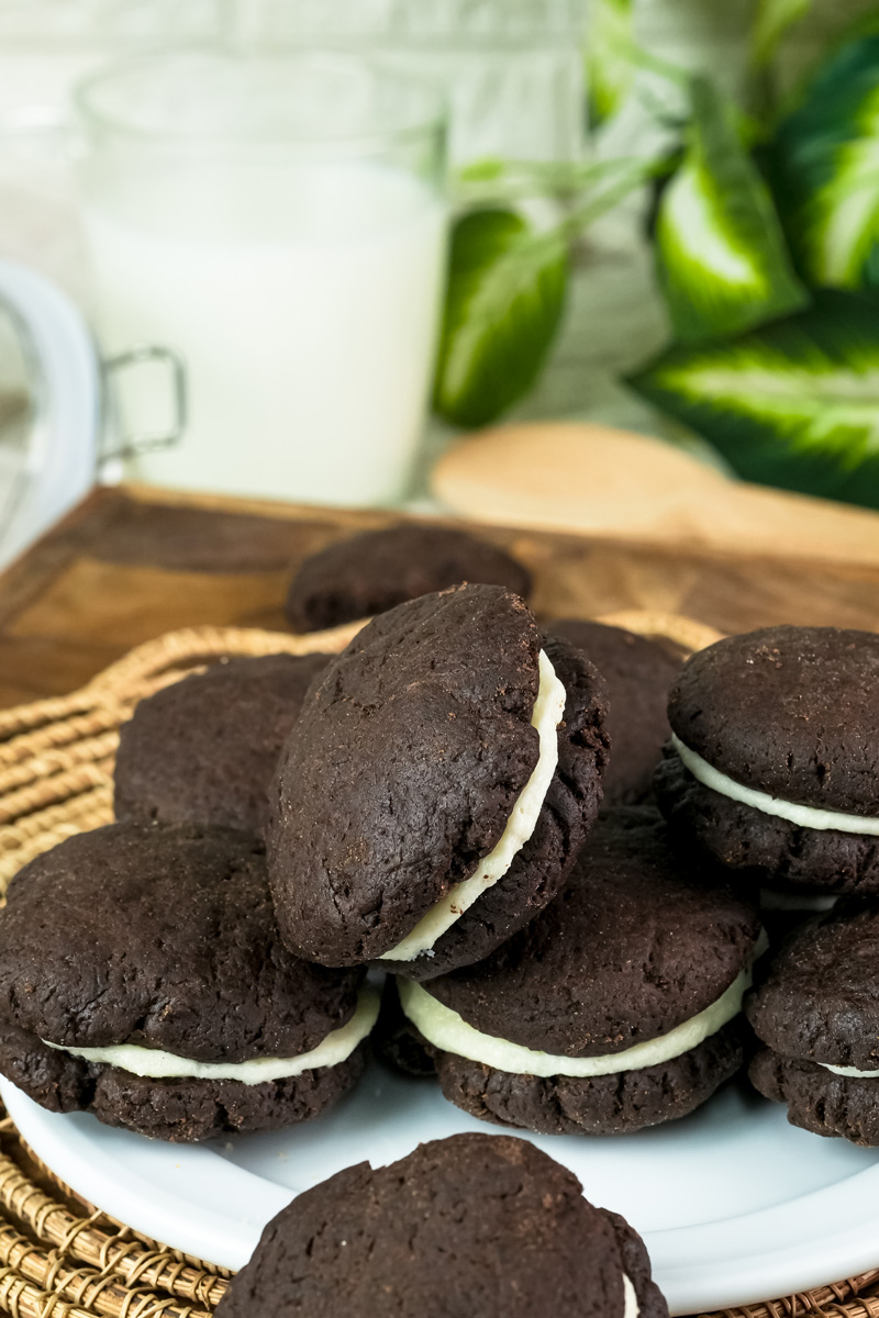A plate of homemade Oreo cookies with a glass of milk in the background