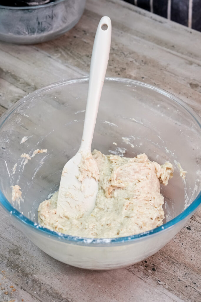 A thick, lumpy banana cookie dough mixture in a glass bowl