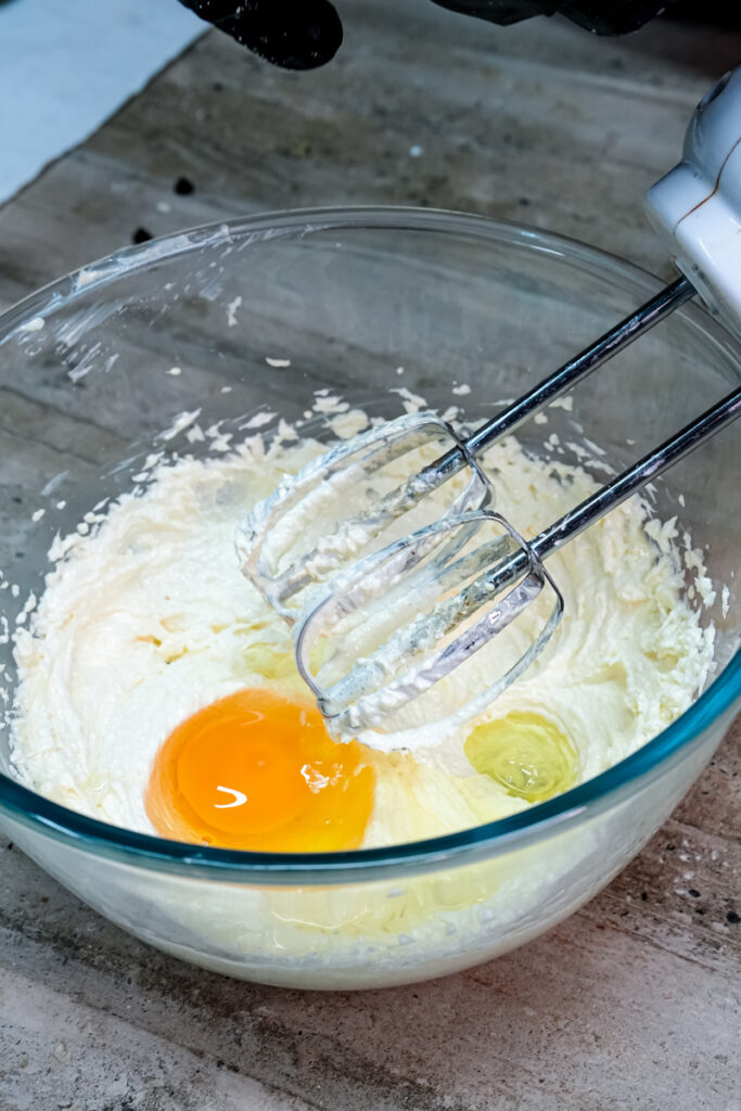 Adding an egg and vanilla extract to the creamed butter and sugar mixture for churro cookie dough