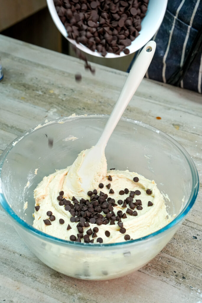Adding chocolate chips to the finished cookie dough