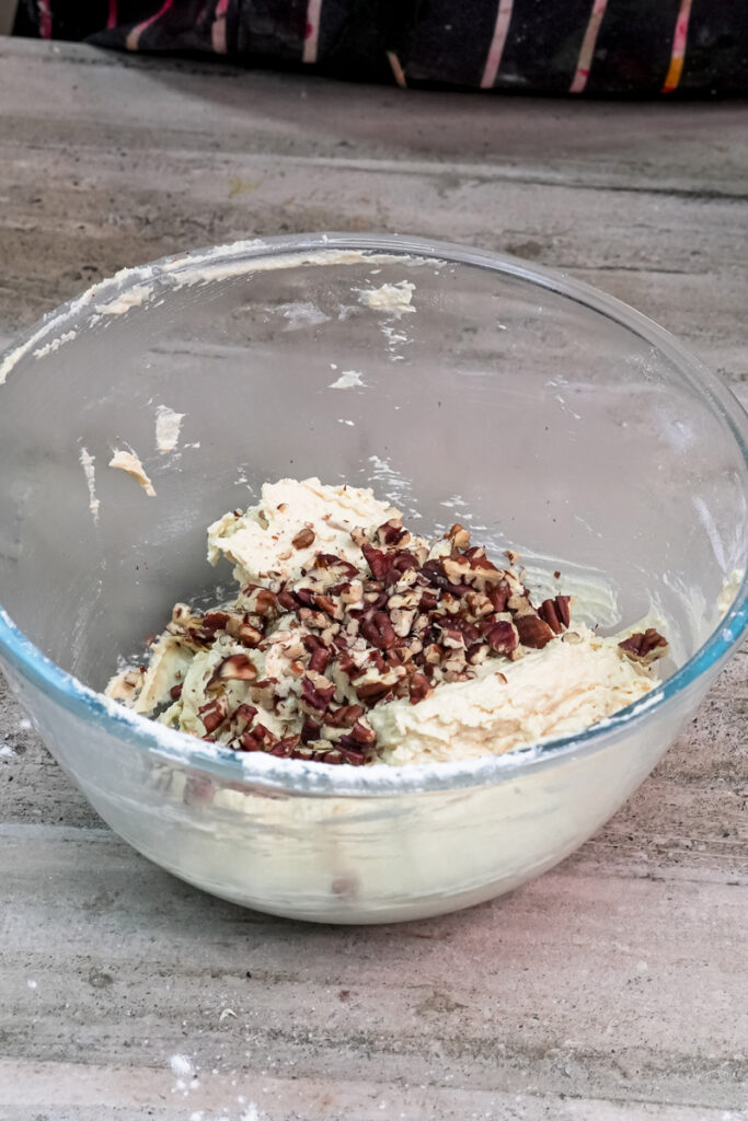 Adding chopped pecans to the cookie dough mixture