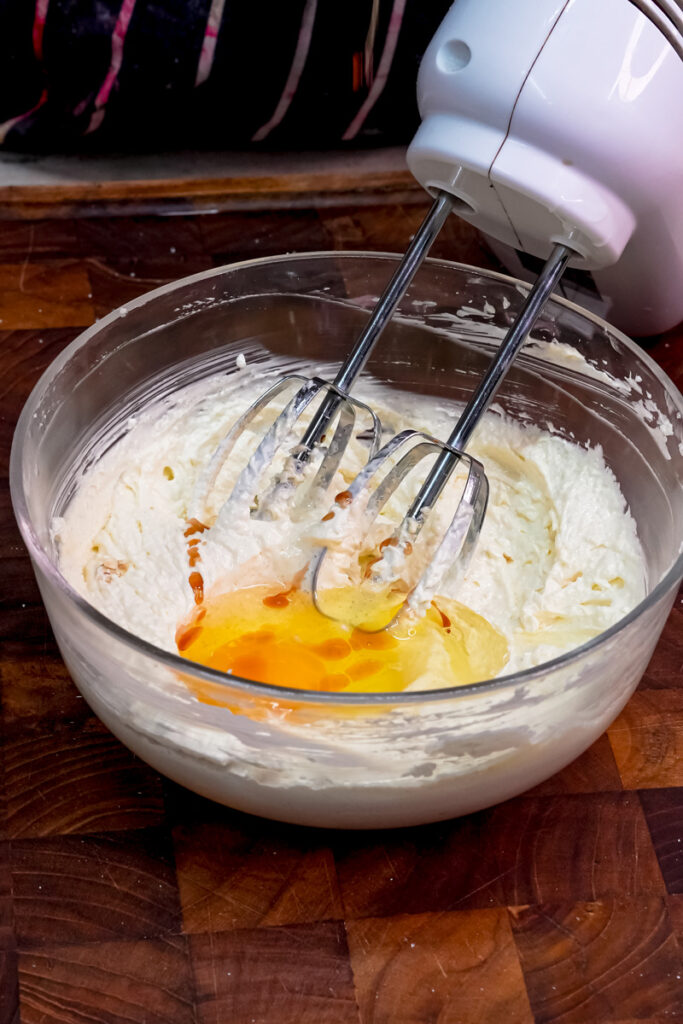 Adding egg and vanilla extract to the creamed butter and sugar mixture