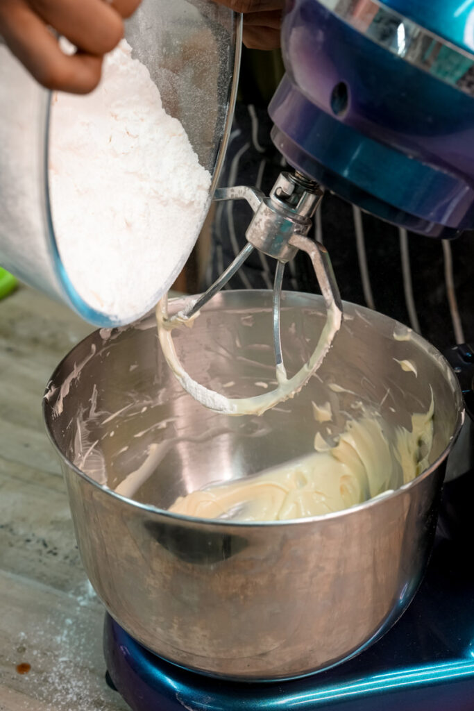 Adding flour to alfajores cookie dough in stand mixer bowl