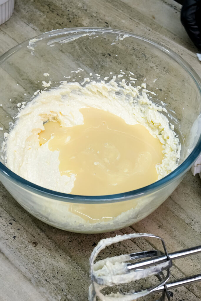Adding milk to cookie dough in glass bowl