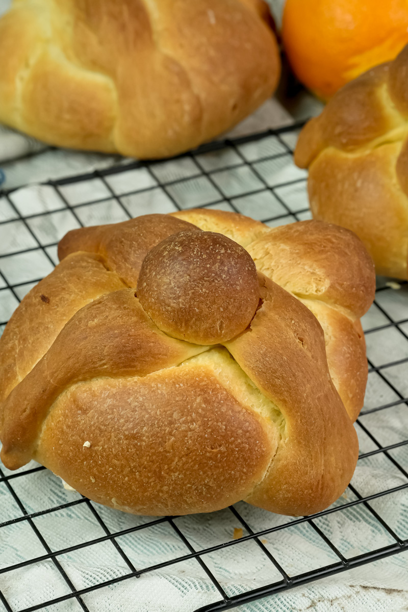 Baked pan de muerto with golden brown crust on cooling rack