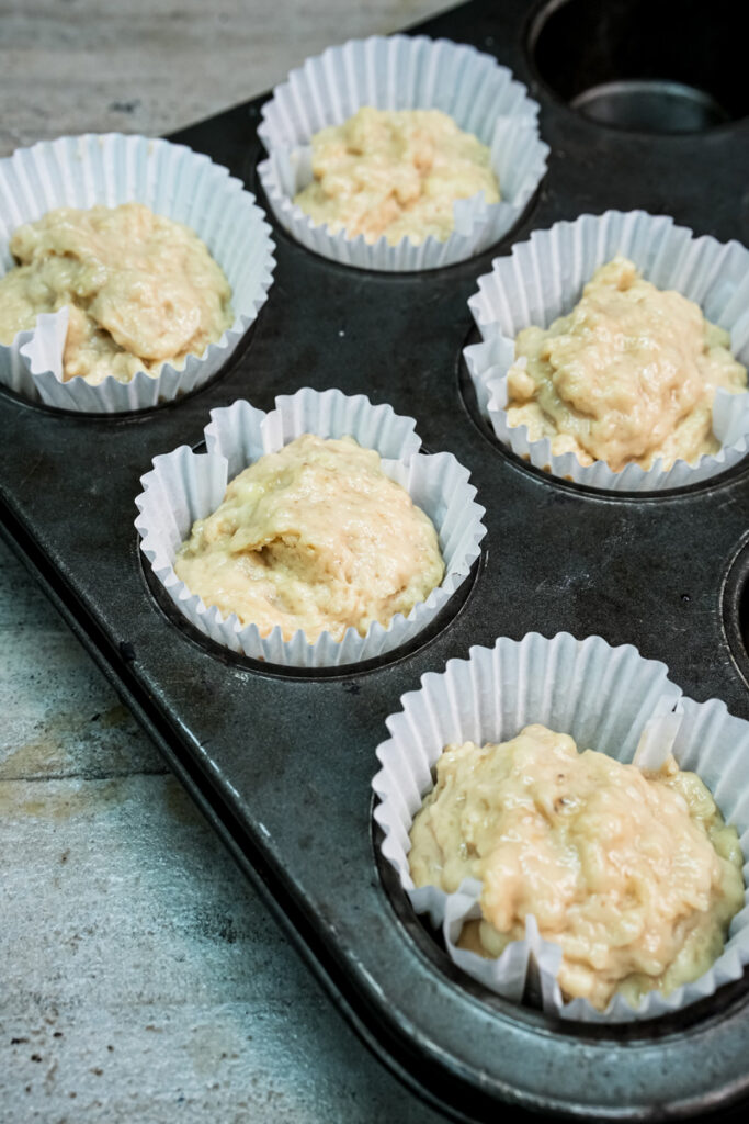 Banana protein muffin batter scooped into six paper-lined muffin cups