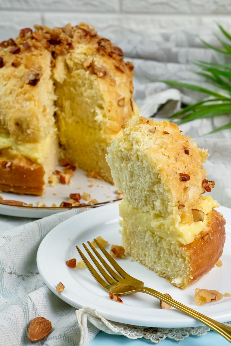 Sliced bee sting cake showing cream filling and golden almond honey topping with gold fork