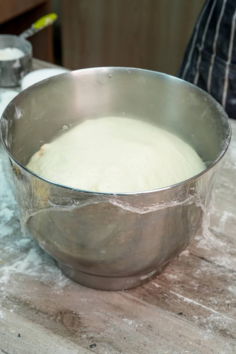 Bread dough rising in covered bowl for pineapple buns