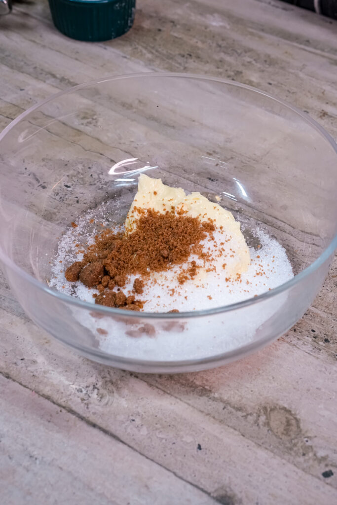 Brown sugar and granulated sugar added to softened butter in a clear bowl