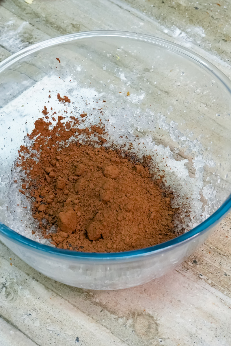 Cocoa powder added to melted butter and sugar for chocolate crinkle cookie dough