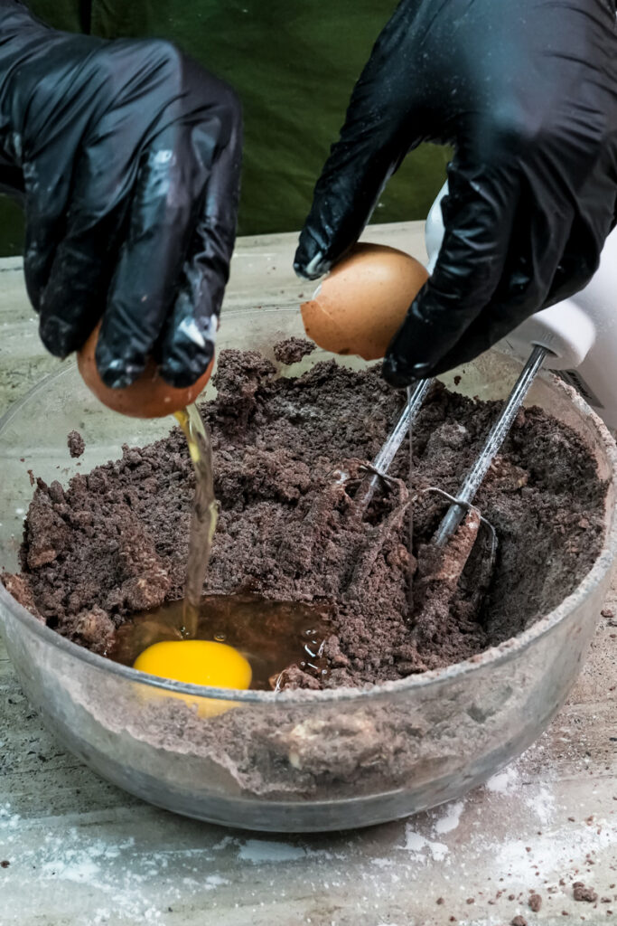 Cracking an egg into the Oreo cookie dough mixture