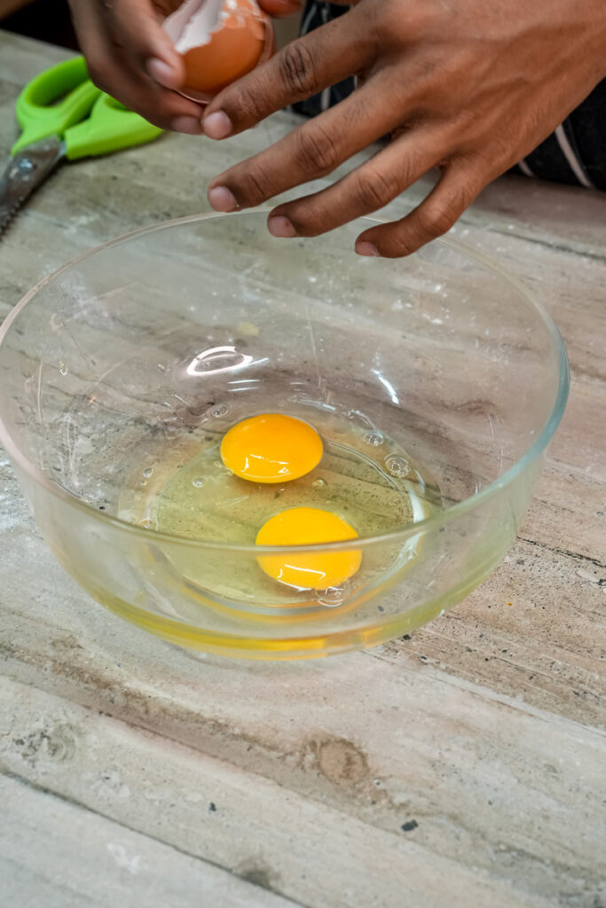 Cracking eggs into glass bowl for pan de muerto recipe