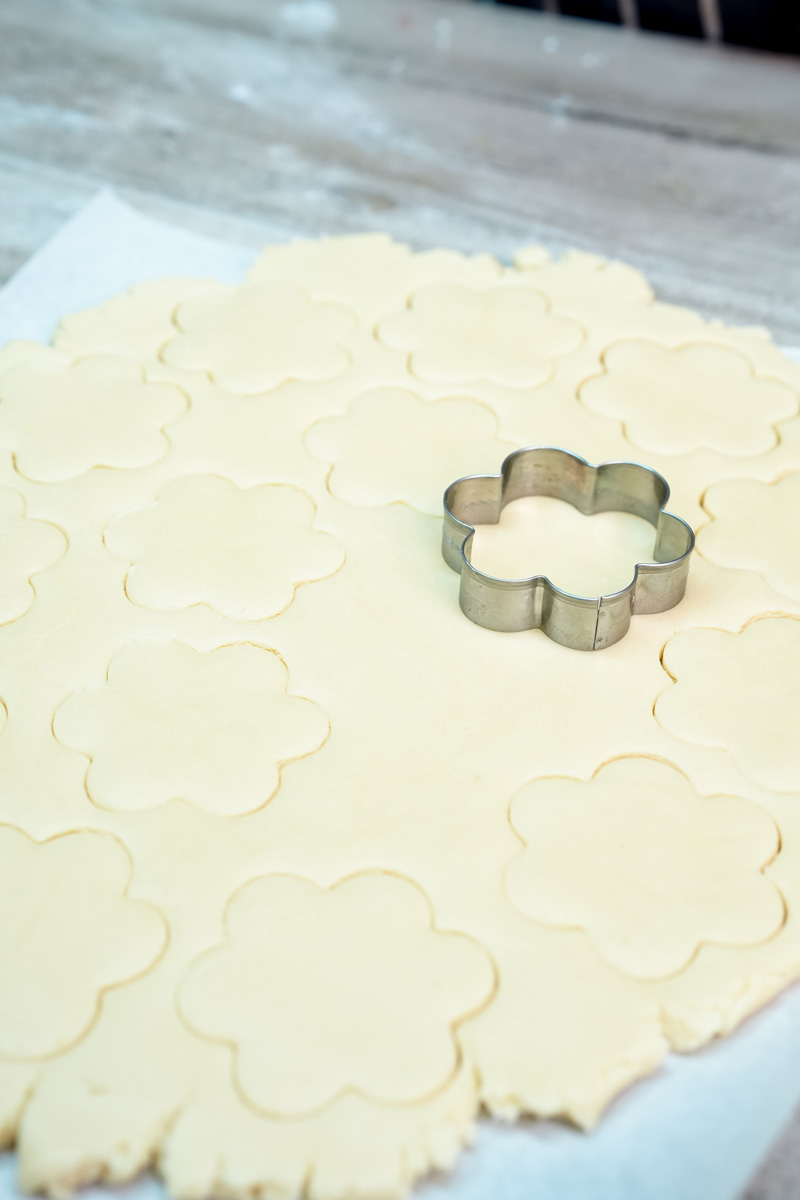 Cutting flower-shaped alfajores cookies with cookie cutter
