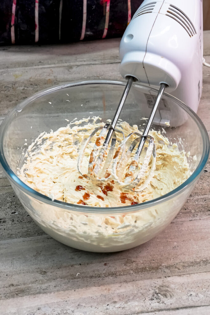 Drizzling vanilla extract into the cookie dough mixture