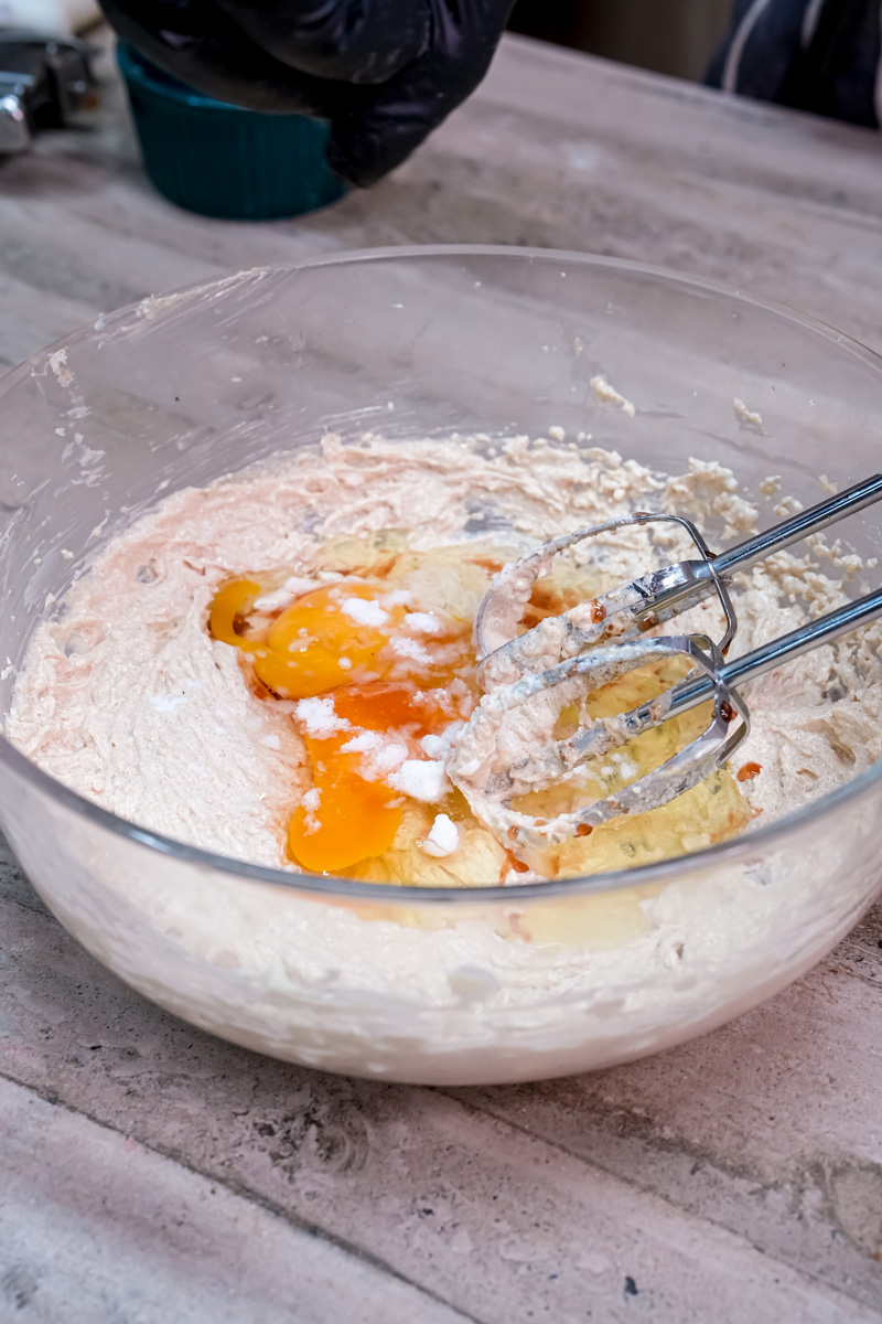 Eggs and vanilla extract being added to the creamed butter and sugar mixture