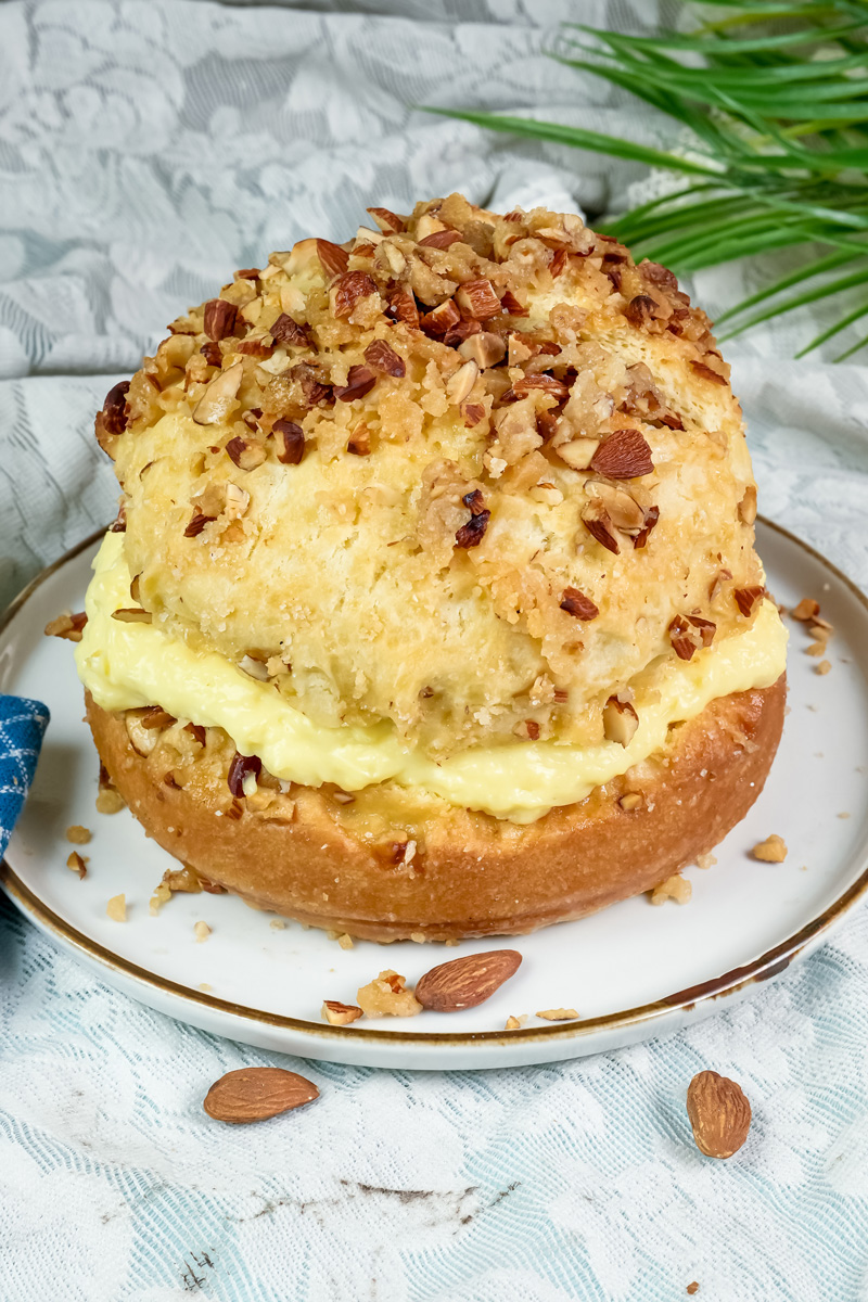 Finished bee sting cake with pastry cream filling and honey almond topping on white plate