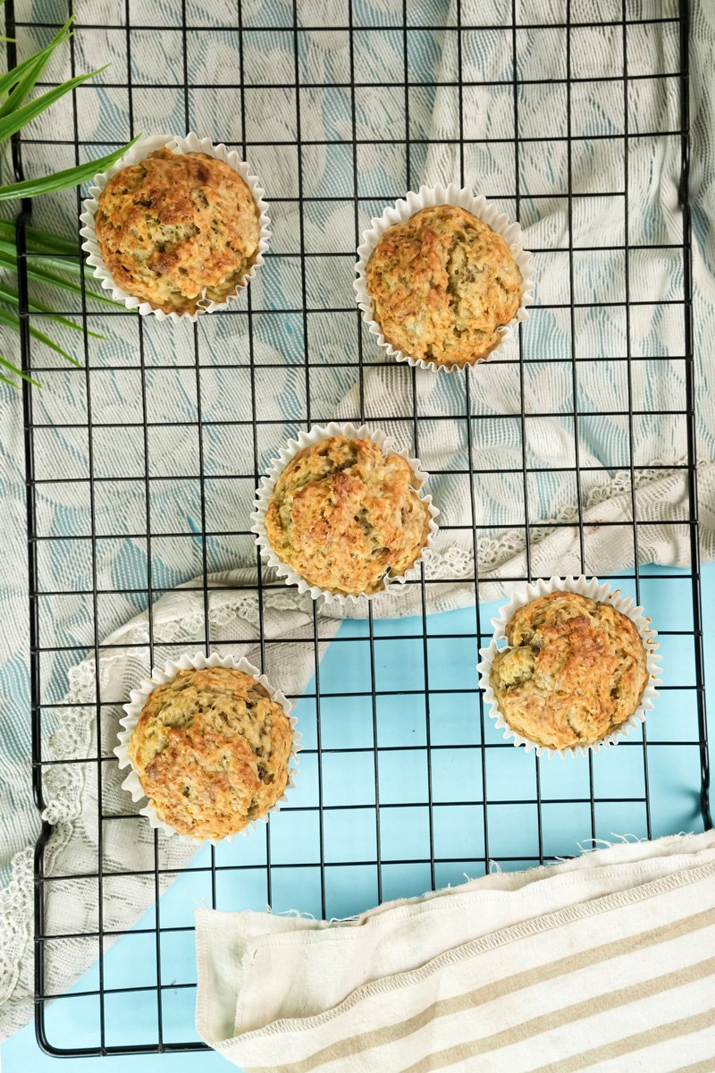 Five baked banana protein muffins from a top-down view on a wire rack