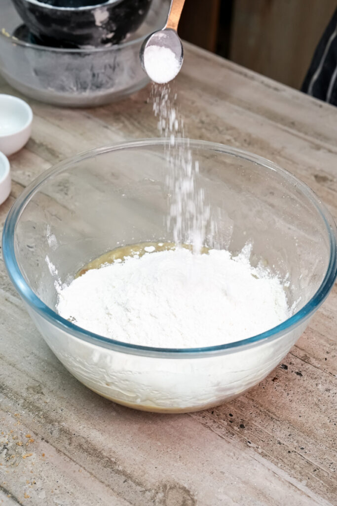 Flour and baking soda being sifted into the banana and sugar mixture