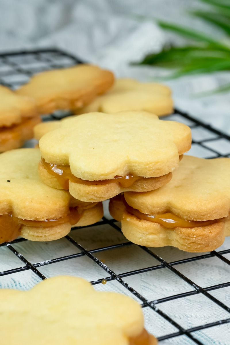 Flower-shaped alfajores cookies with dulce de leche filling on wire rack