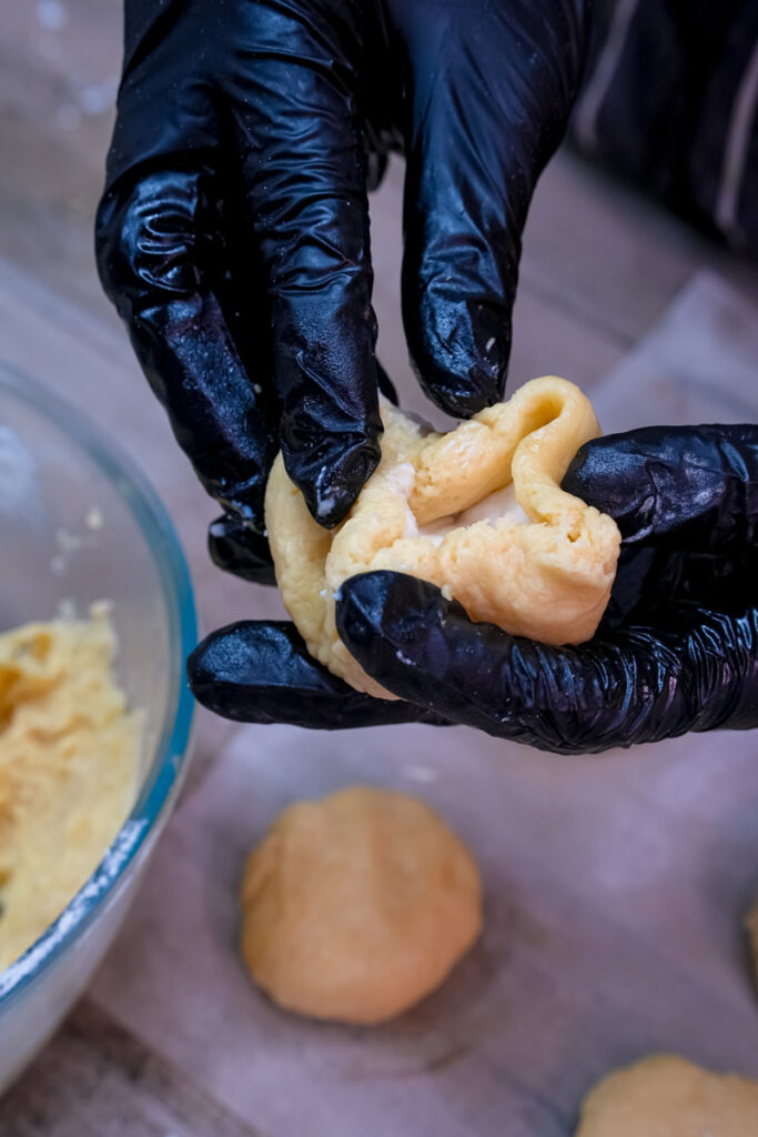 Forming cheesecake cookie dough around cream cheese filling by hand