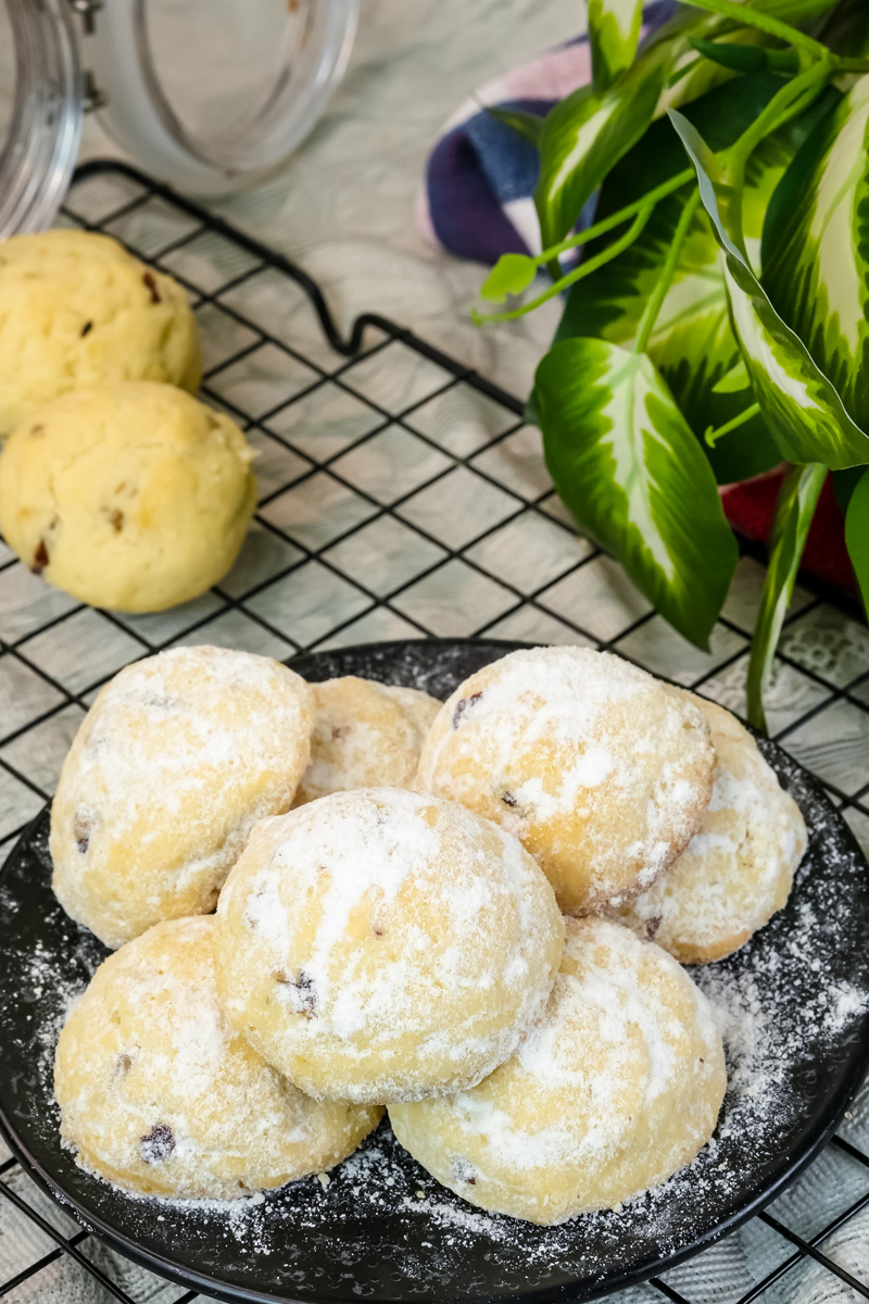 Freshly baked Mexican wedding cookies dusted with powdered sugar on black plate