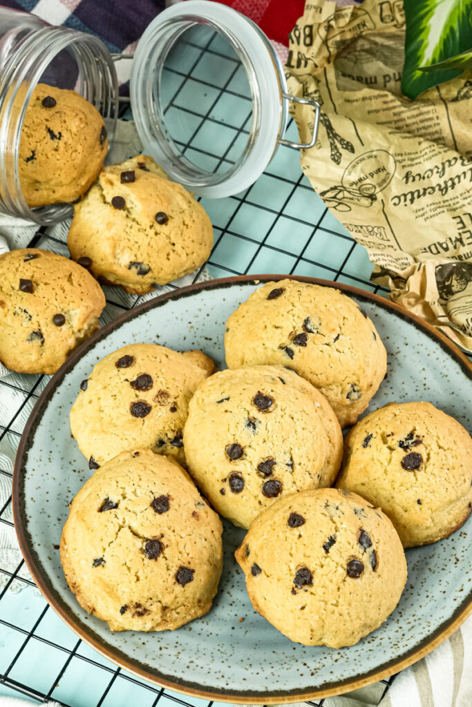 Freshly baked chocolate chip cookies on a gray plate and cooling rack