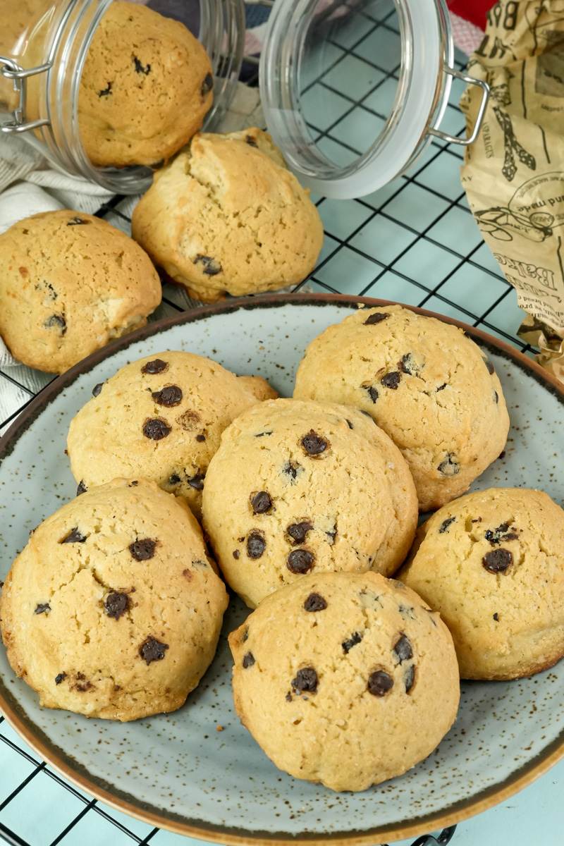 Freshly baked chocolate chip cookies on a plate and cooling rack