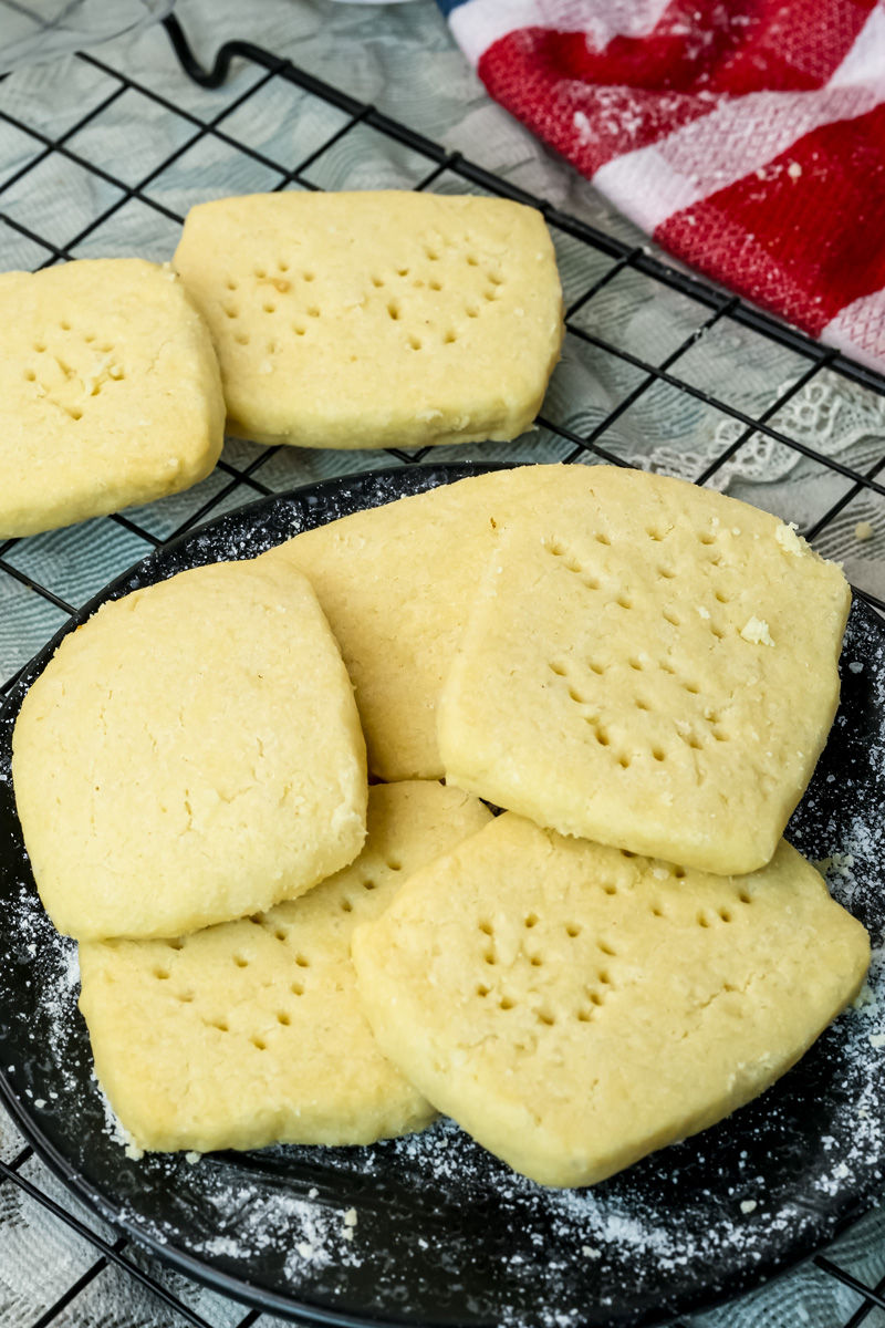Homemade shortbread cookies arranged on black plate and cooling rack