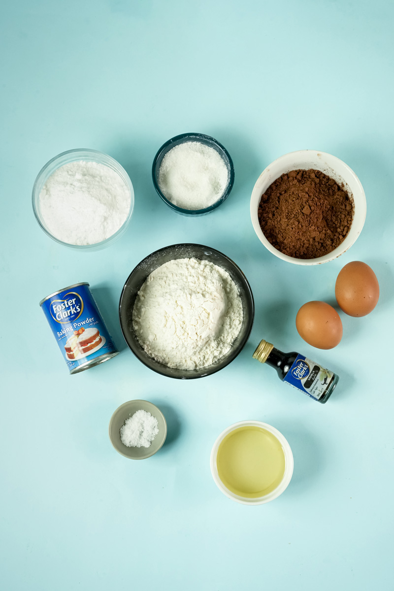 Ingredients for chocolate crinkle cookies, including cocoa powder, flour, sugar, and eggs.